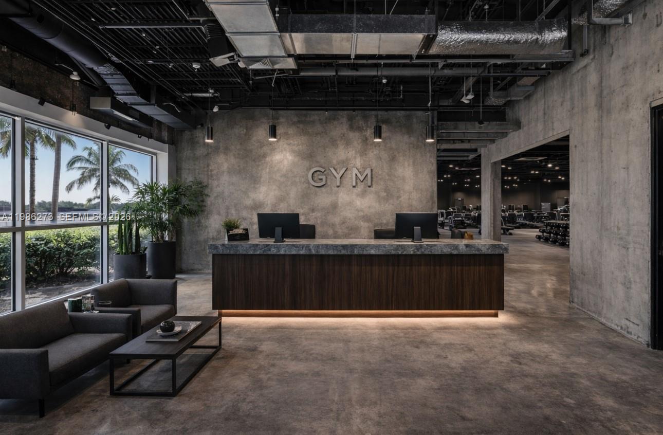 A modern gym reception area features a concrete wall, dark wood desk, and lounge seating — 2950 N 28th Ter, Hollywood FL 33020, HOLLYWOOD, FL
