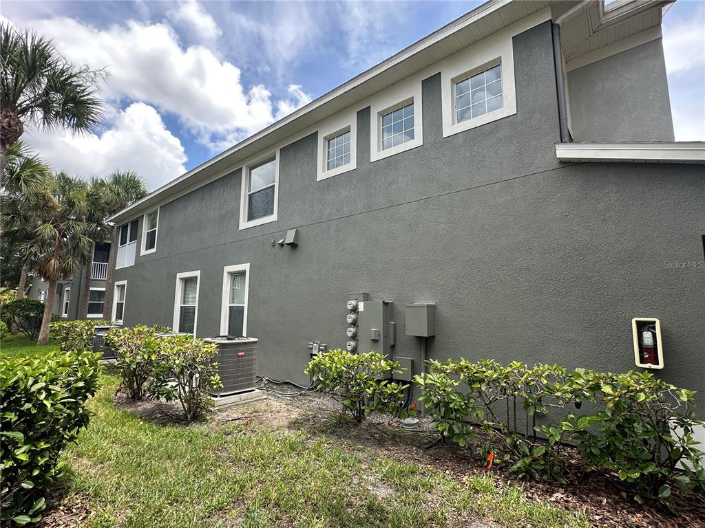 The exterior side of a multi-story gray stucco building features several windows and HVAC units — 2146 RIVER TURIA CIRCLE UNIT N/A, RIVERVIEW, FL