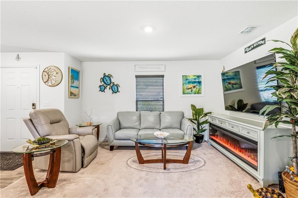 A living room features a grey sofa, a matching recliner, and an electric fireplace console — SEBASTIAN, FL
