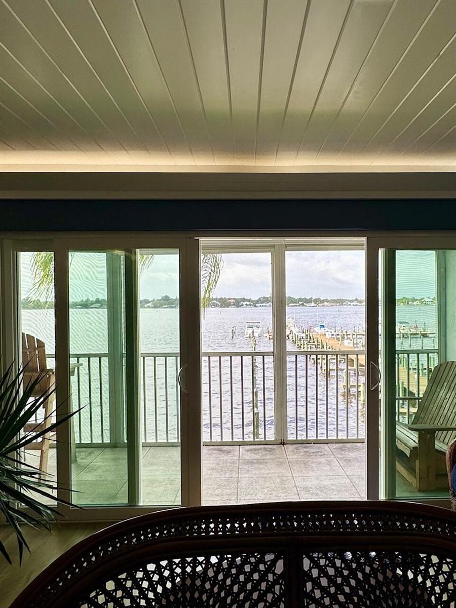 A view of a waterfront balcony through large sliding glass doors from an indoor room — 1868 SW Palm City Road # 202, Stuart FL 34994, STUART, FL