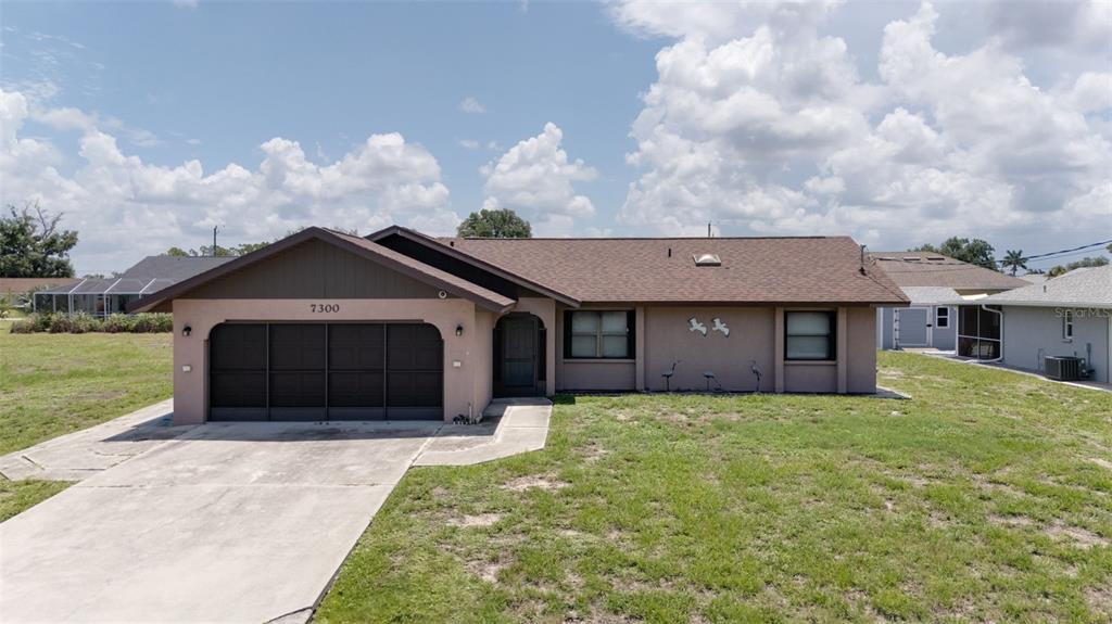 A single-story house with a brown roof, tan stucco exterior, and a two-car garage — 7300 BEARDSLEY STREET, ENGLEWOOD, FL