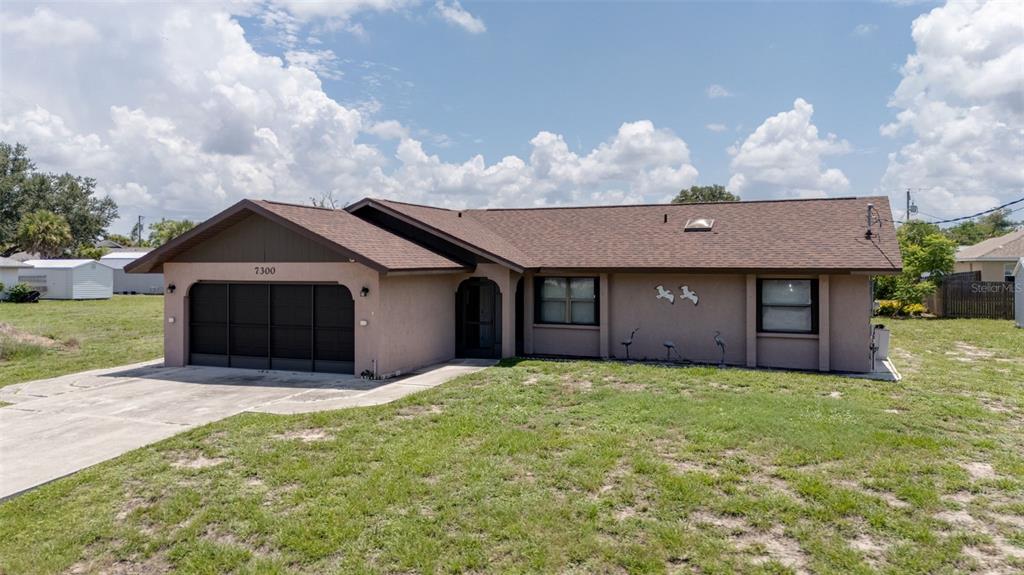 A single-story house with a brown roof, tan stucco exterior, and a two-car garage — 7300 BEARDSLEY STREET, ENGLEWOOD, FL