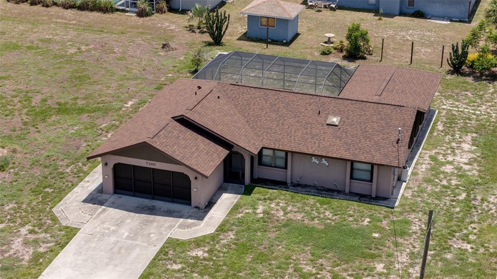 An aerial view of a single-story house with a brown roof and a screened-in pool — 7300 BEARDSLEY STREET, ENGLEWOOD, FL
