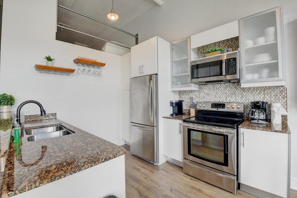 A modern kitchen features stainless steel appliances, granite countertops, and white cabinetry — 185 NE 4th Avenue # 210, Delray Beach FL 33483, DELRAY BEACH, FL