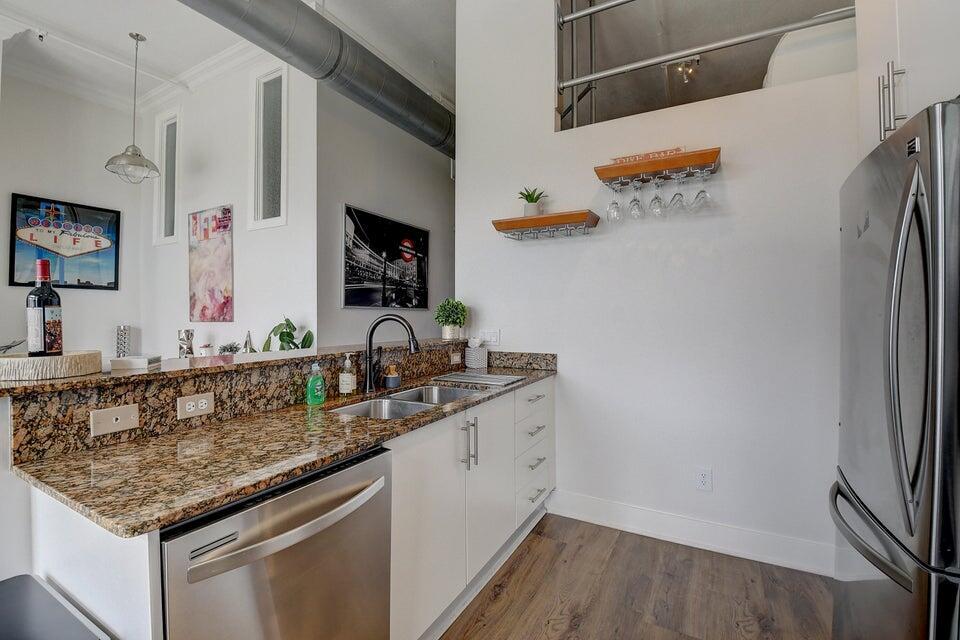 A kitchen features granite countertops, white cabinets, stainless steel appliances, and a wine glass rack — 185 NE 4th Avenue # 210, Delray Beach FL 33483, DELRAY BEACH, FL