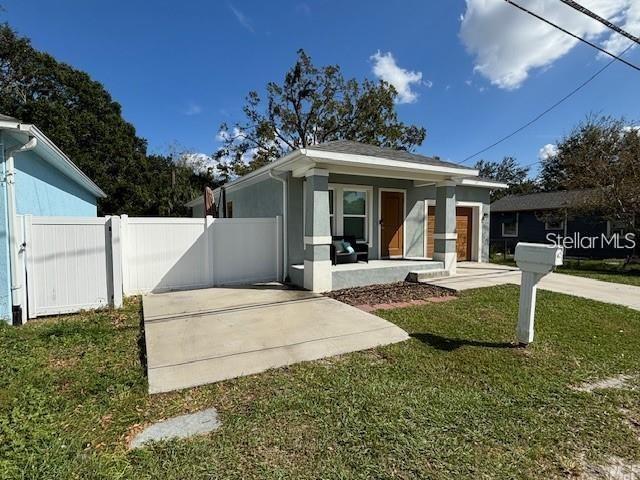 A single-story house with a front porch, concrete driveway, and white vinyl privacy fence — 4303 N 30TH STREET, TAMPA, FL