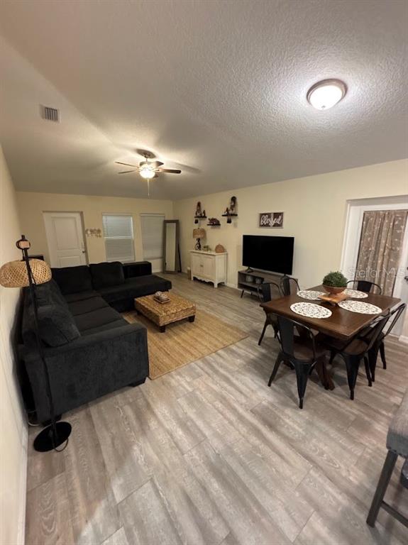 A living and dining area features a dark sectional sofa, wood-look flooring, and a television — 4303 N 30TH STREET, TAMPA, FL