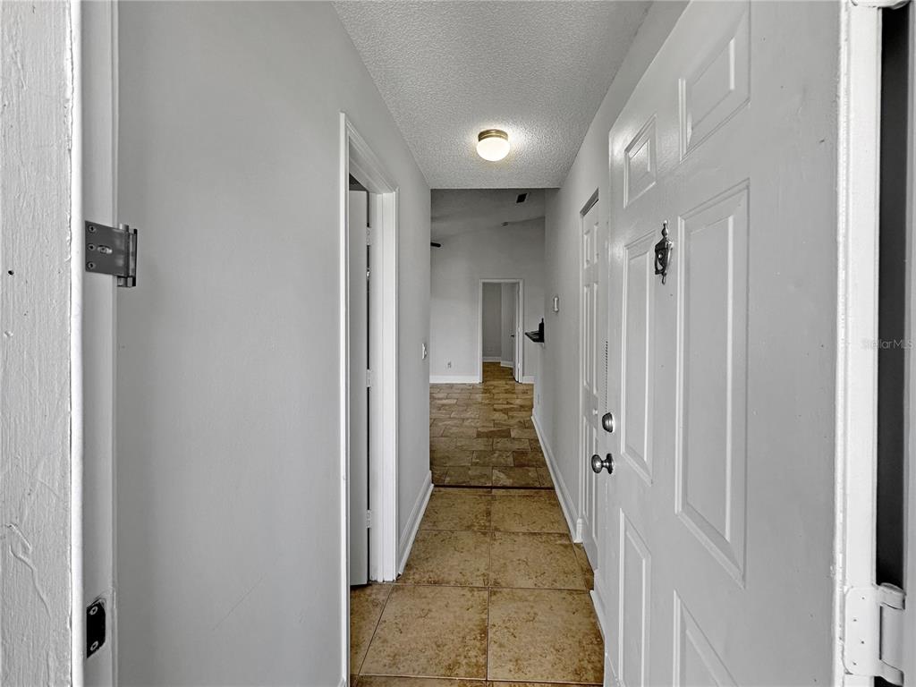 A hallway with tile flooring leads from an entryway toward a living area — 708 SECRET HARBOR LANE UNIT 204, LAKE MARY, FL
