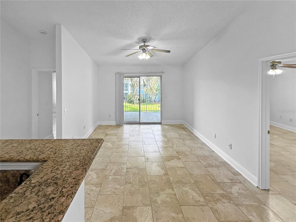 A living area with tile flooring, a ceiling fan, and sliding glass doors to a patio — 708 SECRET HARBOR LANE UNIT 204, LAKE MARY, FL