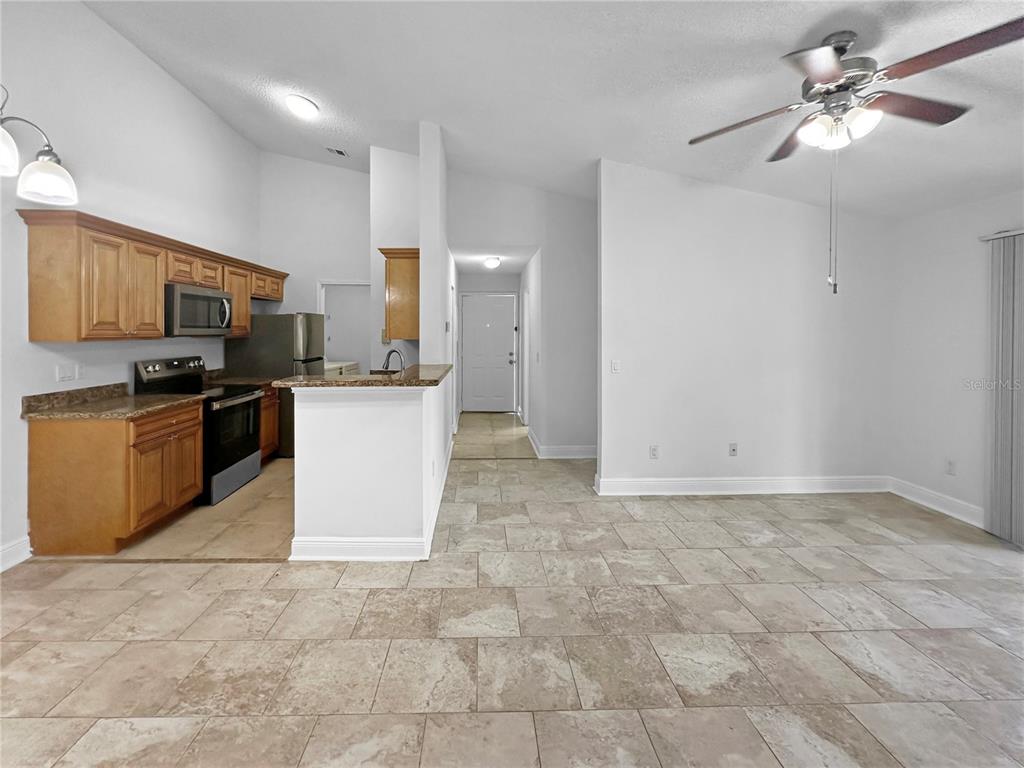 A kitchen with wood cabinets and a breakfast bar opens into a tiled dining area — 708 SECRET HARBOR LANE UNIT 204, LAKE MARY, FL