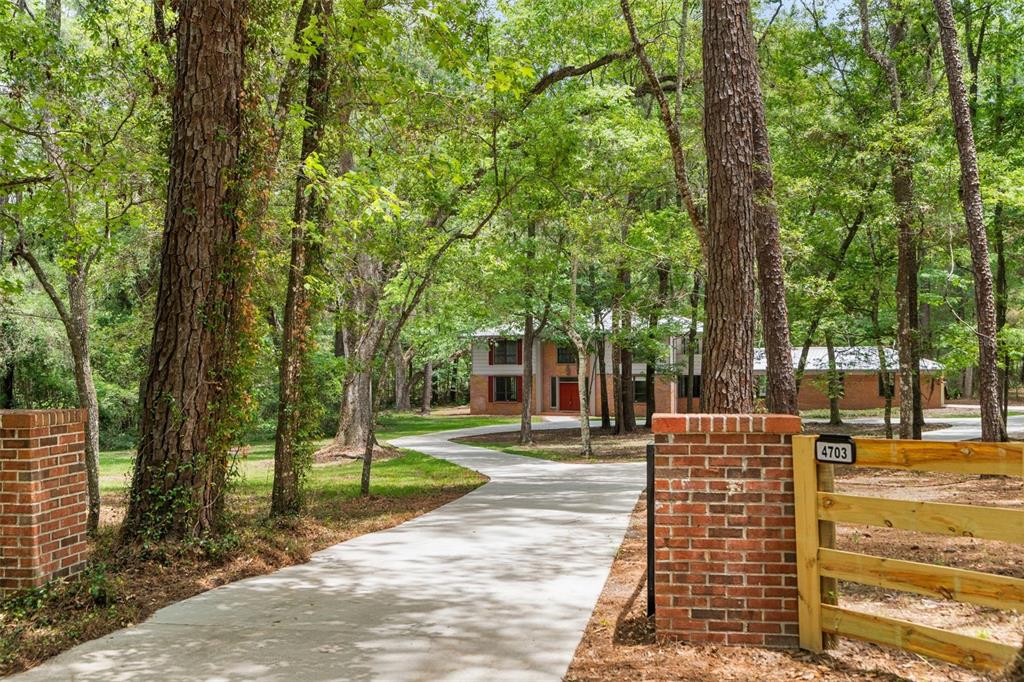 A concrete driveway leads through a wooded yard to a two-story brick house — 4703 NW 124TH STREET, GAINESVILLE, FL