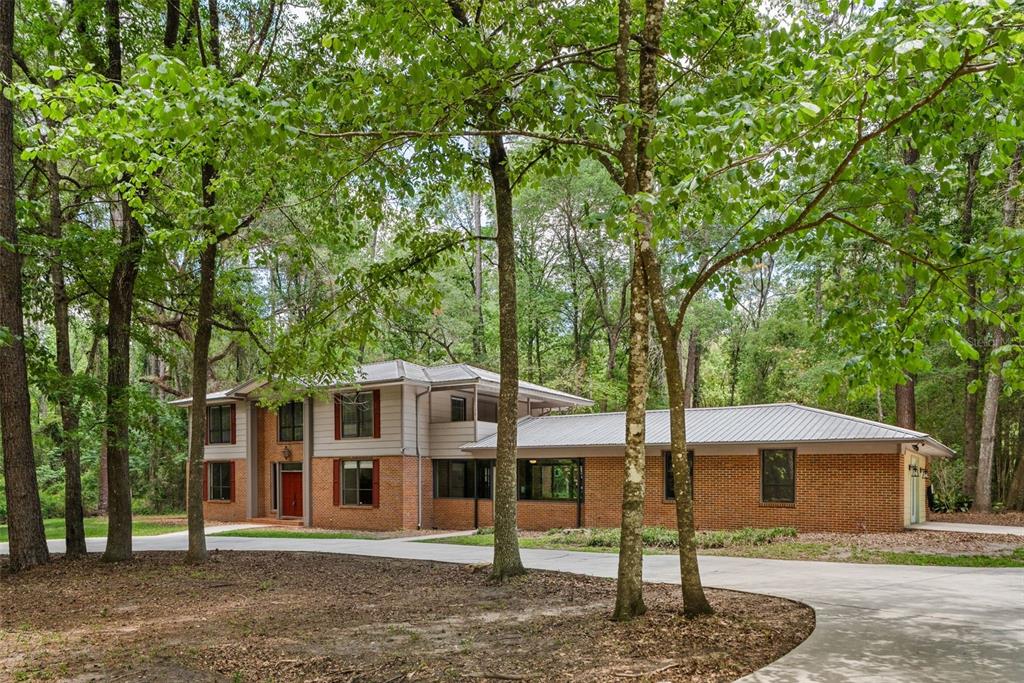 A two-story house with brick and siding exterior sits in a wooded lot — 4703 NW 124TH STREET, GAINESVILLE, FL