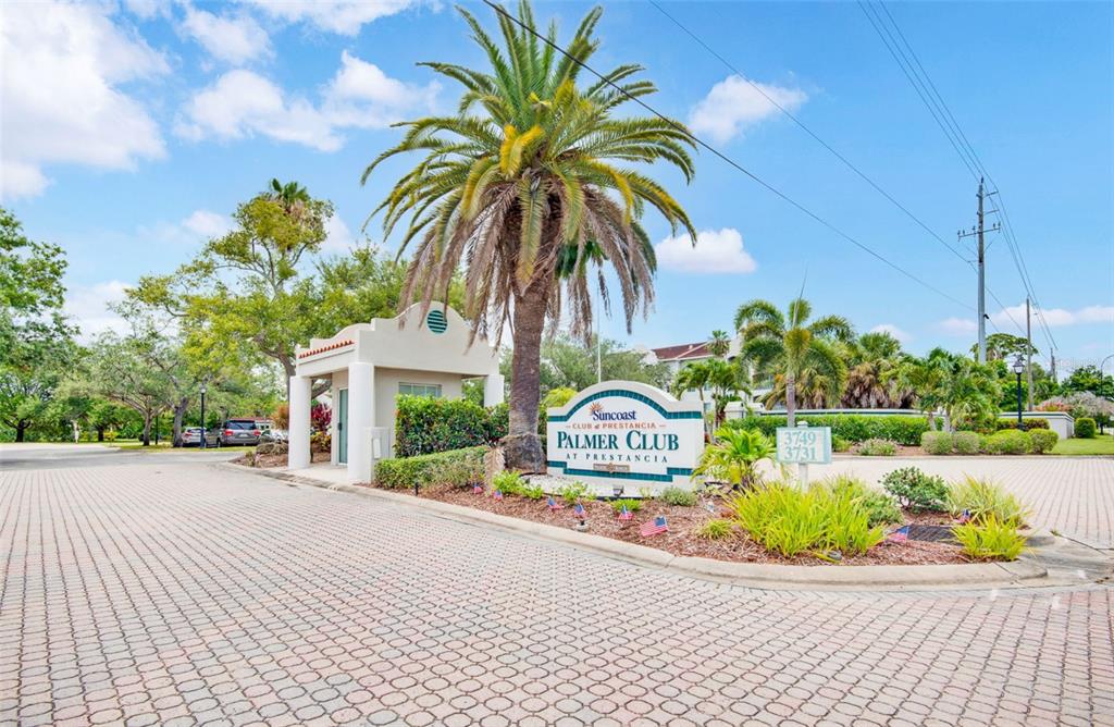 The exterior entrance of a multi-story building features a covered walkway with benches and planters — 3731 SARASOTA SQUARE BOULEVARD UNIT 205D, SARASOTA, FL