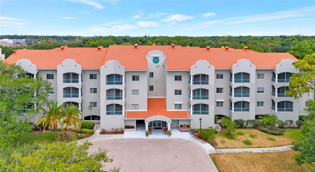 A bright lobby features tile flooring, two pairs of chairs, potted plants, and double exit doors — 3731 SARASOTA SQUARE BOULEVARD UNIT 205D, SARASOTA, FL