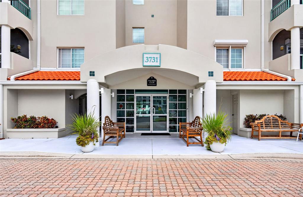 An elevator lobby features tiled floors, light-colored walls with chair rail molding, and a potted plant — 3731 SARASOTA SQUARE BOULEVARD UNIT 205D, SARASOTA, FL