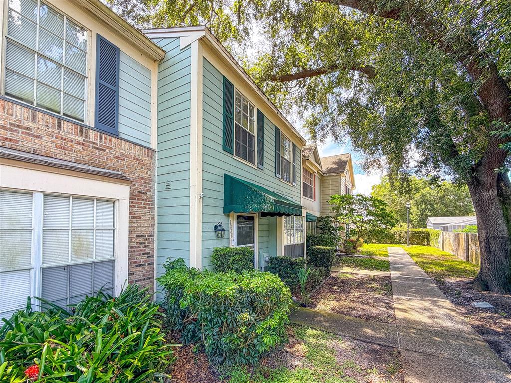 A two-story townhouse with light green siding, brick accents, and a green fabric awning — 1844 MILL RUN CIRCLE, TAMPA, FL