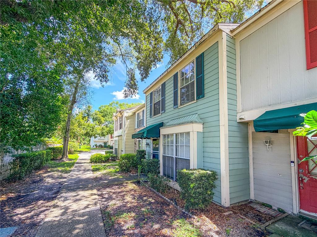 A sidewalk leads past the exterior of two-story townhouses with green siding and green awnings — 1844 MILL RUN CIRCLE, TAMPA, FL
