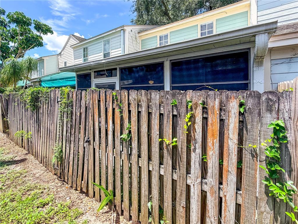 A weathered wooden fence runs along the side of a house with a screened-in porch — 1844 MILL RUN CIRCLE, TAMPA, FL