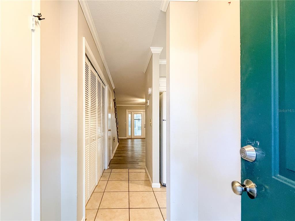 A view from a doorway looking down a hallway with tile flooring and louvered closet doors — 1844 MILL RUN CIRCLE, TAMPA, FL