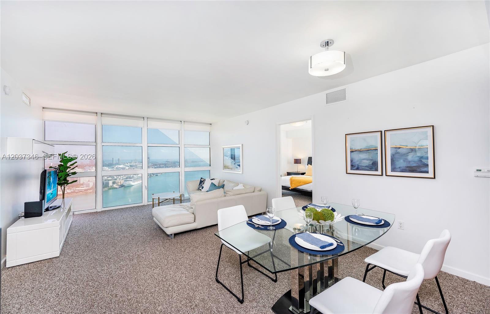 A bright living and dining area features floor-to-ceiling windows with a harbor view — 50 Biscayne Blvd # 4104, Miami FL 33132, MIAMI, FL