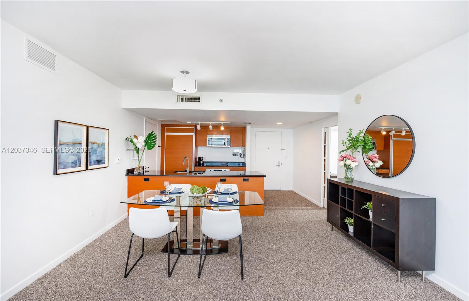 A dining area with a glass table and white chairs sits before an open kitchen — 50 Biscayne Blvd # 4104, Miami FL 33132, MIAMI, FL