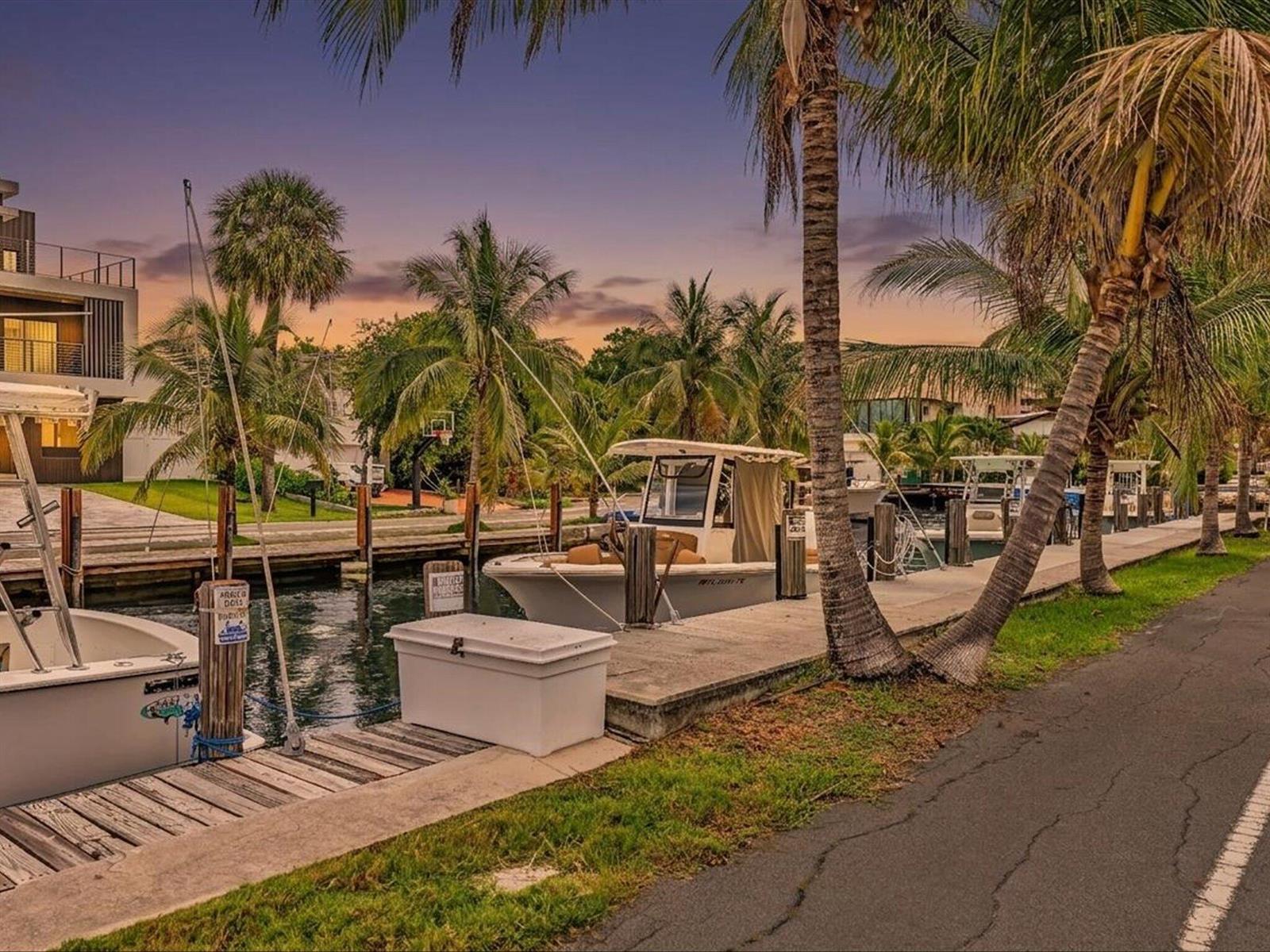 A canal with docked boats and palm trees at sunset next to a paved path — 3232 Canal Drive # 19, Pompano Beach FL 33062, POMPANO BEACH, FL