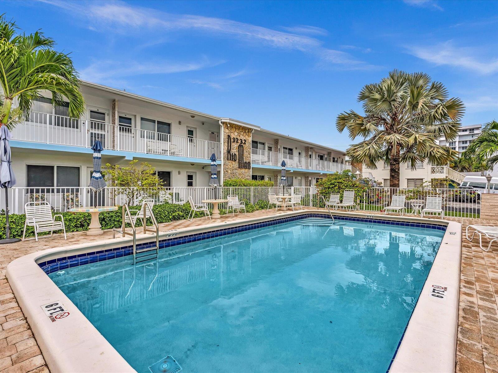 A rectangular swimming pool sits in front of a two-story motel building with palm trees — 3232 Canal Drive # 19, Pompano Beach FL 33062, POMPANO BEACH, FL