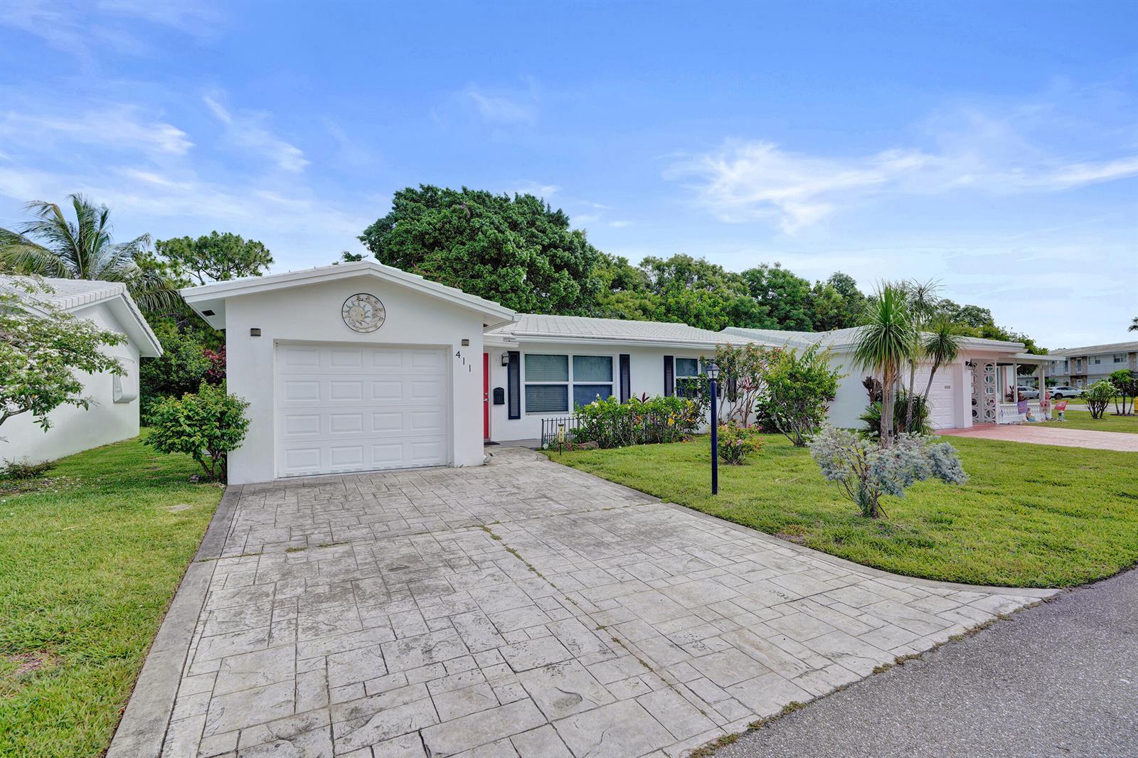A white single-story house with a stamped concrete driveway and a one-car garage — 411 NW 26th Court, Pompano Beach FL 33064, POMPANO BEACH, FL