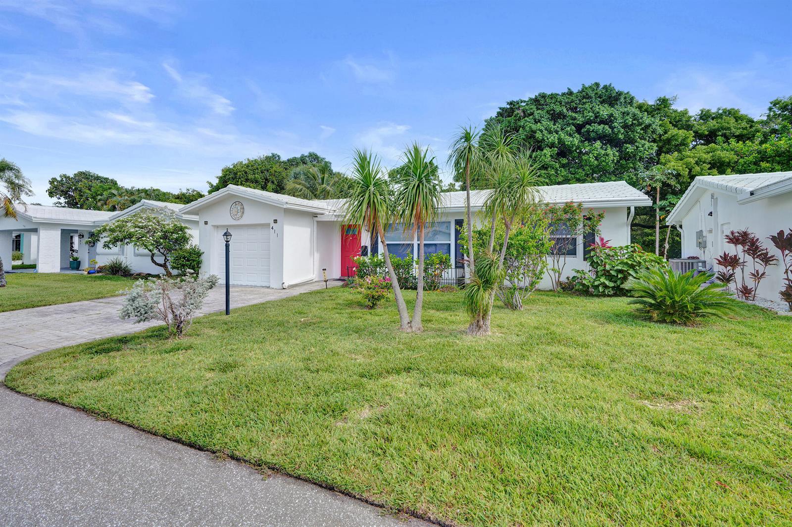 A white single-story house with a red front door, a garage, and a front lawn — 411 NW 26th Court, Pompano Beach FL 33064, POMPANO BEACH, FL