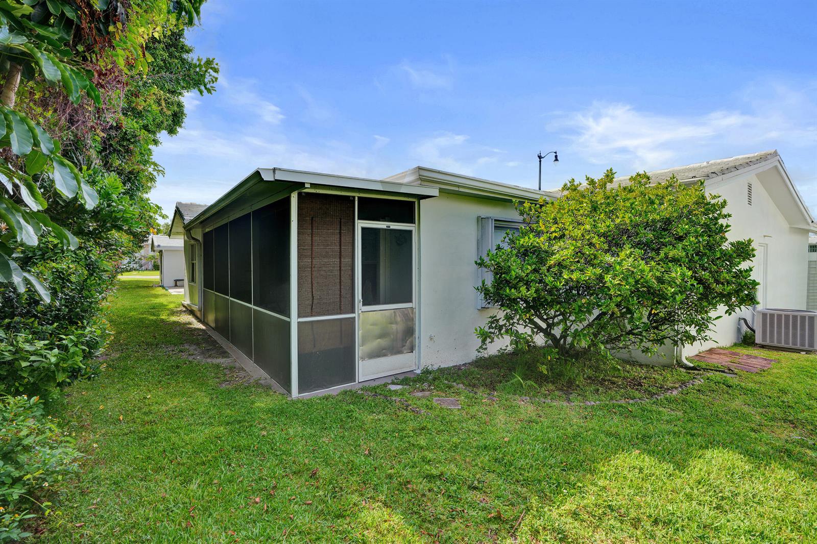 The exterior of a white house features a screened-in porch and a large green bush — 411 NW 26th Court, Pompano Beach FL 33064, POMPANO BEACH, FL