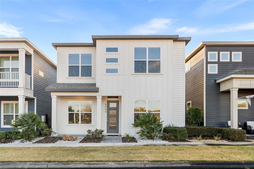 A two-story house with white vertical siding, a gray front door, and a small front yard — 6464 SW 77TH STREET, GAINESVILLE, FL