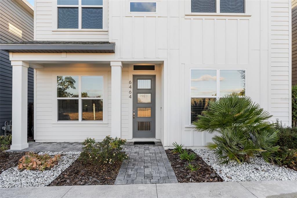 A modern white house exterior features a gray front door and a paved walkway — 6464 SW 77TH STREET, GAINESVILLE, FL