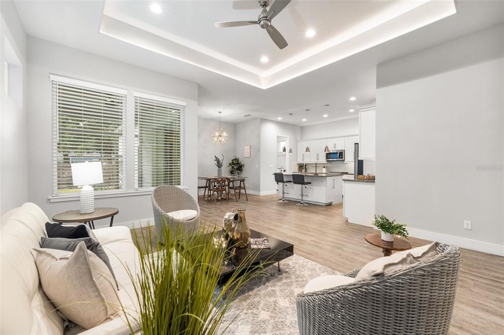 An open-concept living room and kitchen feature light wood flooring and a tray ceiling — 6464 SW 77TH STREET, GAINESVILLE, FL