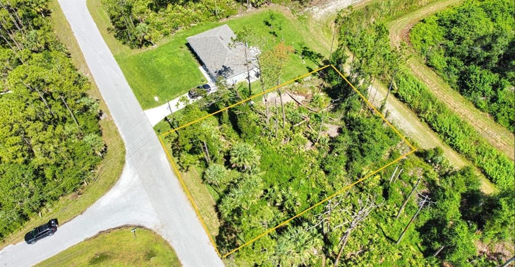 An aerial view shows a vacant, wooded lot outlined in yellow next to a house — ARMENIA ROAD, NORTH PORT, FL