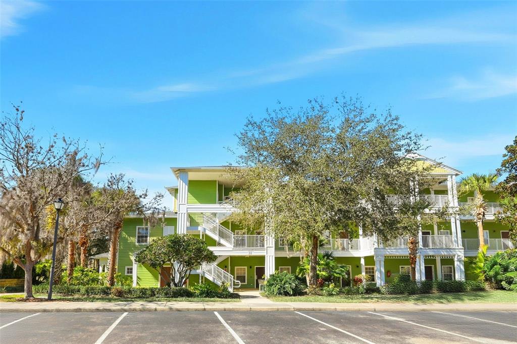 A three-story apartment building with lime green siding and white exterior staircases faces a parking lot — 1014 GRAN BAHAMA BOULEVARD UNIT 31-1014, DAVENPORT, FL