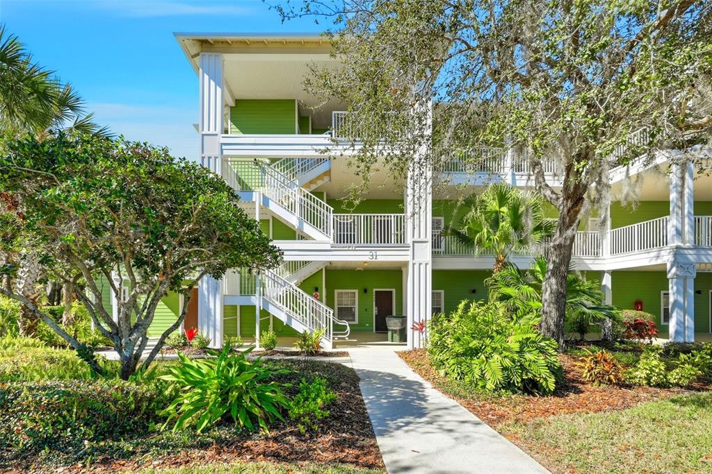 A three-story apartment building with green siding and an exterior staircase under a blue sky — 1014 GRAN BAHAMA BOULEVARD UNIT 31-1014, DAVENPORT, FL