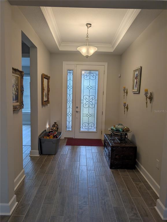 An entryway features a front door with decorative glass, tile flooring, and a tray ceiling — 285 BELLA CORTINA DRIVE, POINCIANA, FL