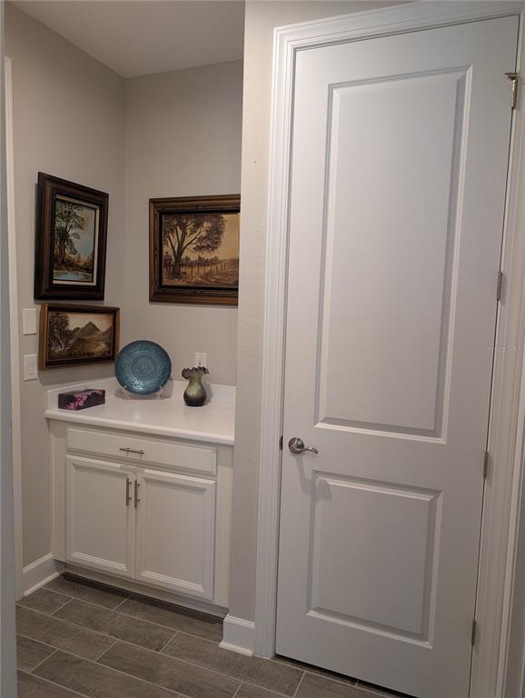 A small alcove features a white cabinet, countertop, wall art, and a closed interior door — 285 BELLA CORTINA DRIVE, POINCIANA, FL
