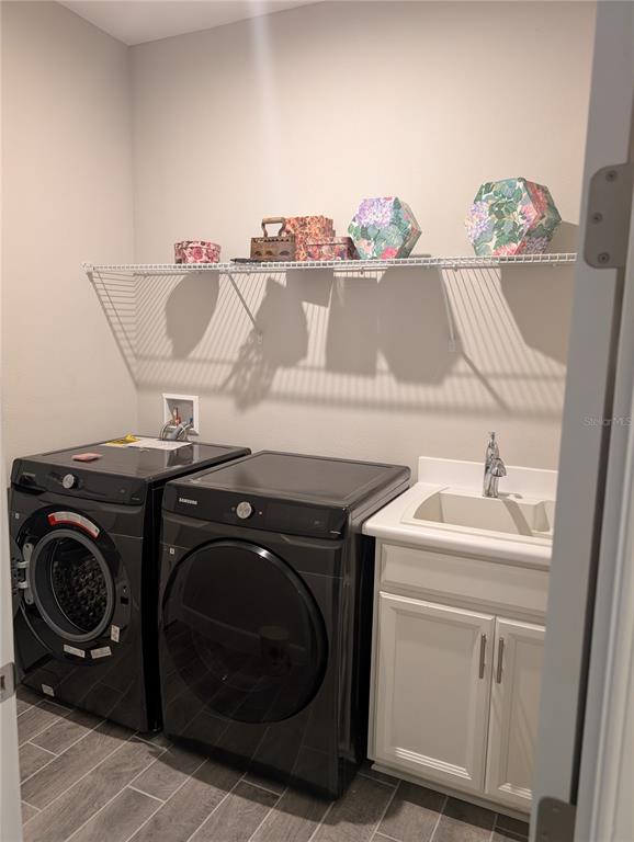 A laundry room features dark appliances, a white utility sink, and a wire wall shelf — 285 BELLA CORTINA DRIVE, POINCIANA, FL