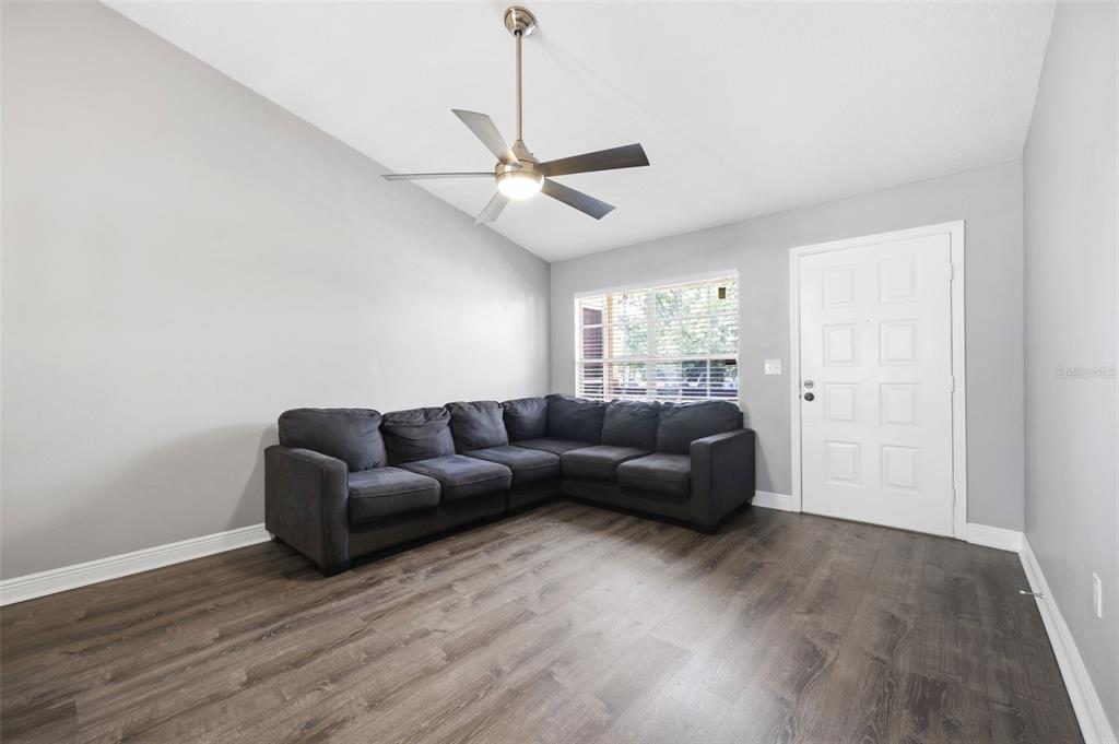 A living room features gray walls, wood-look flooring, a sectional sofa, and a ceiling fan — 7807 HARDWICK DRIVE UNIT 126, NEW PORT RICHEY, FL