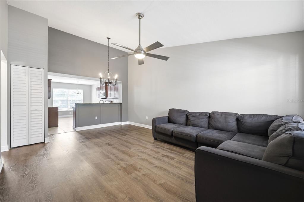A living room with gray walls, wood-look flooring, a ceiling fan, and a sectional sofa — 7807 HARDWICK DRIVE UNIT 126, NEW PORT RICHEY, FL