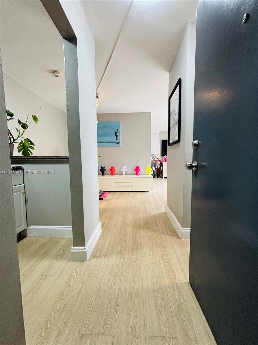 A view from an entryway into a living area with light wood-look flooring — 1255 Collins Ave # 208, Miami Beach FL 33139, MIAMI BEACH, FL