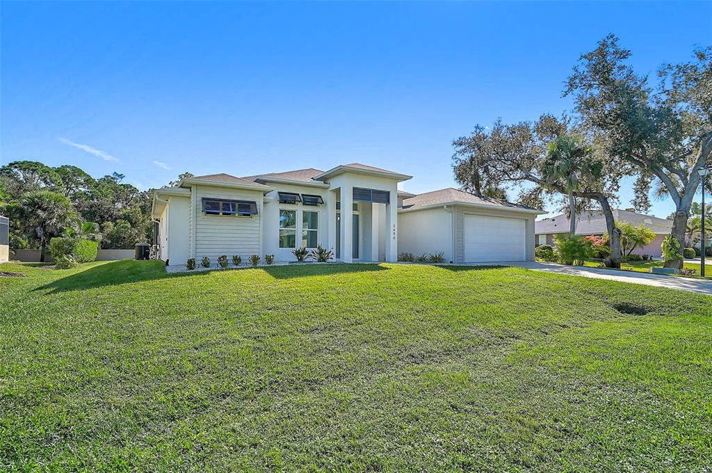 A single-story house with a white exterior, a two-car garage, and a large front lawn — 2690 PEBBLE CREEK PLACE, PORT CHARLOTTE, FL