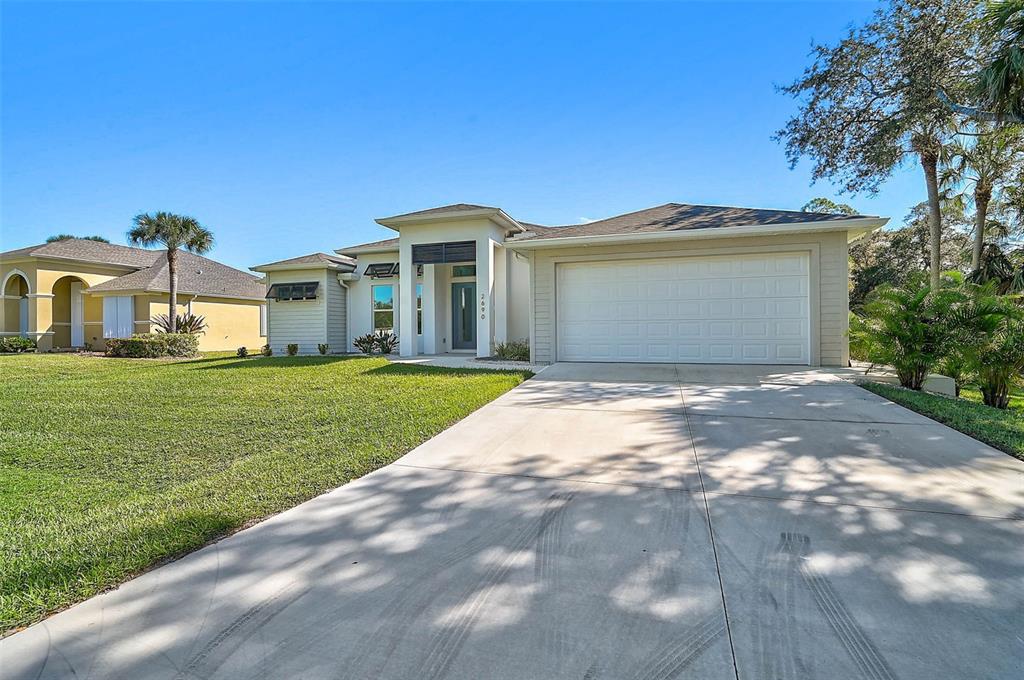 A single-story house with a beige exterior, a two-car garage, and a concrete driveway — 2690 PEBBLE CREEK PLACE, PORT CHARLOTTE, FL