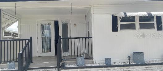 A white mobile home exterior features a small front porch with black railings and stairs — 313 DANUBE CIRCLE, BRADENTON, FL
