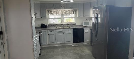 A kitchen features light gray cabinets, stainless steel appliances, and dark gray flooring — 313 DANUBE CIRCLE, BRADENTON, FL