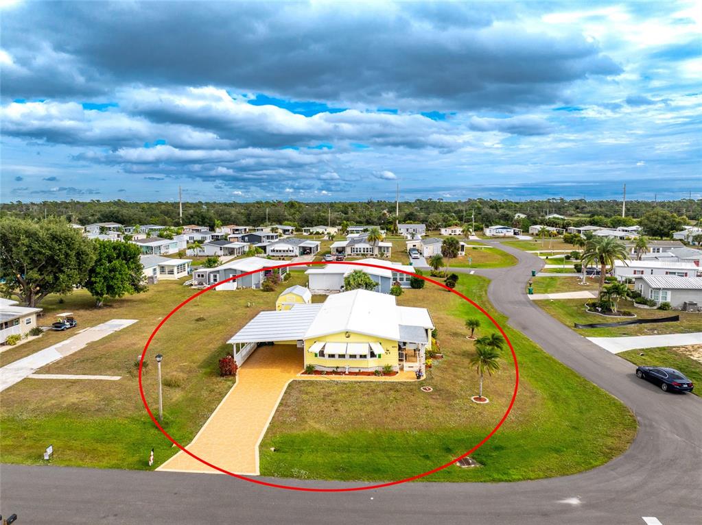 An aerial view shows a yellow manufactured home with a carport and driveway — 6290 GREENFINCH ROAD, ENGLEWOOD, FL