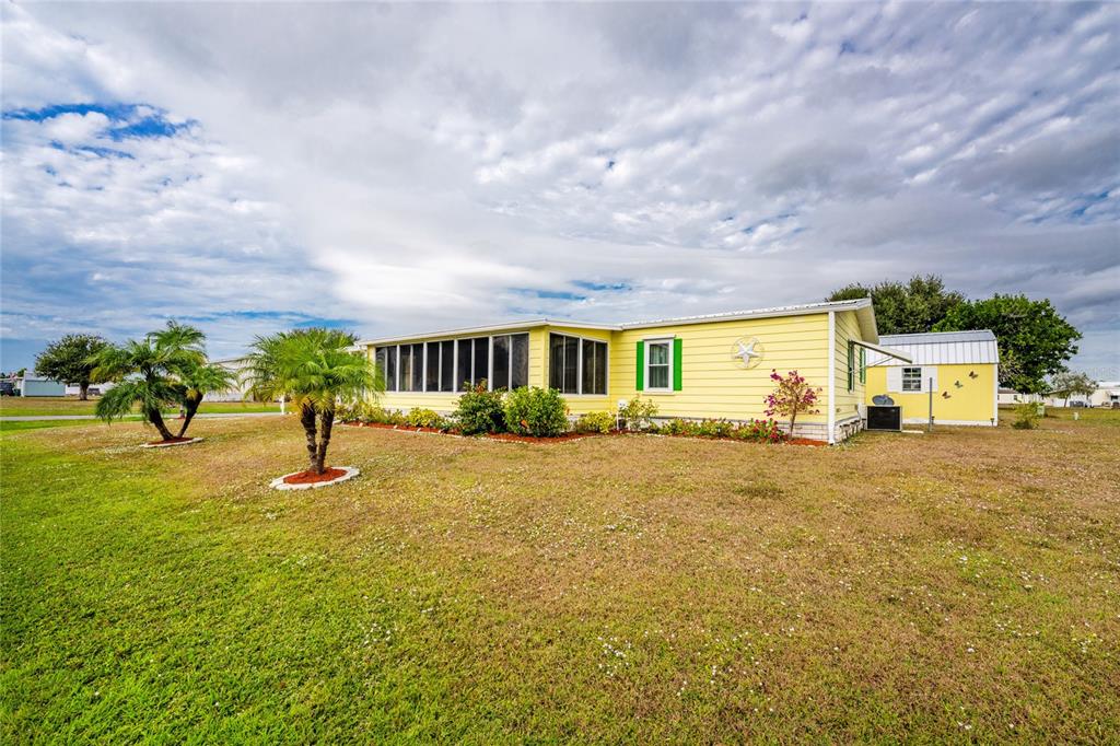 A yellow manufactured home with a screened-in porch sits on a grassy lot — 6290 GREENFINCH ROAD, ENGLEWOOD, FL