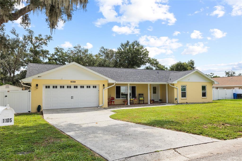 A yellow single-story house with a two-car garage and a concrete driveway — 1103 RIDGEFIELD DRIVE, VALRICO, FL