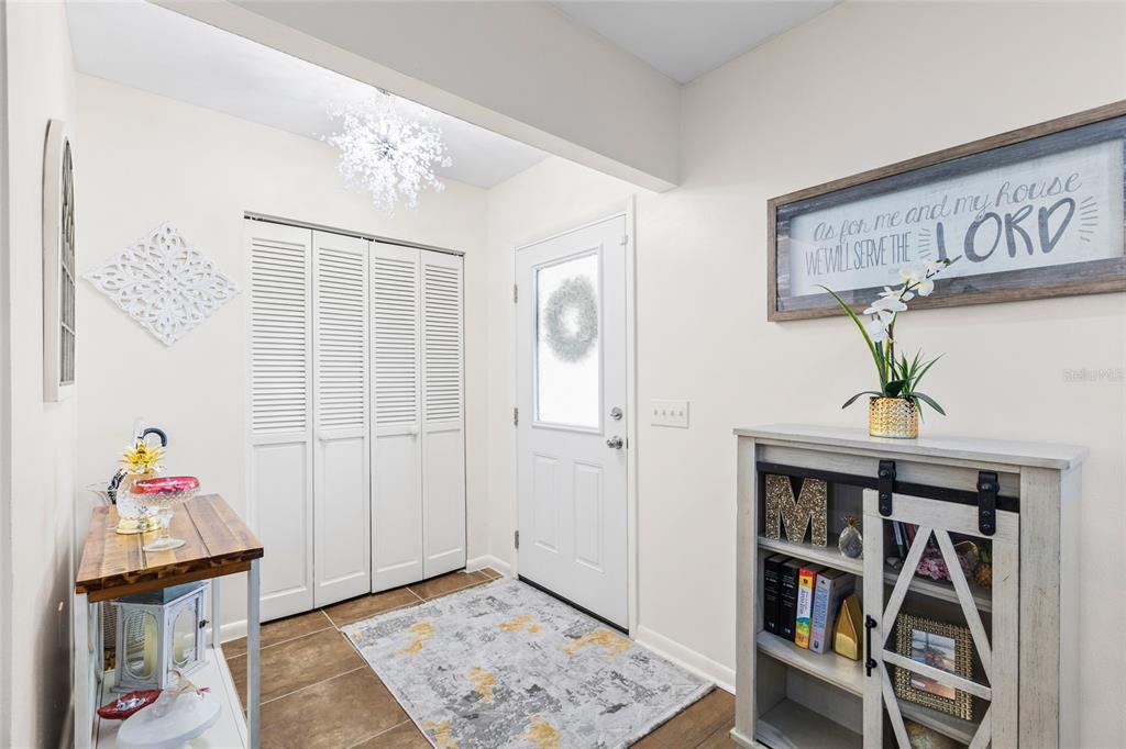 An entryway features white louvered closet doors, a front door, and a wooden console table — 1103 RIDGEFIELD DRIVE, VALRICO, FL